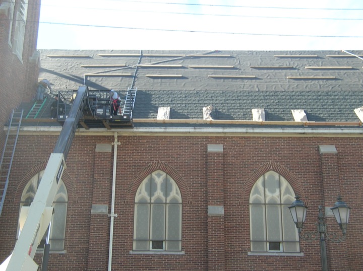 Old brick building being reroofed with the help of machinery