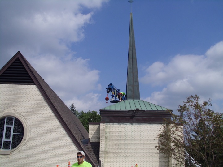 Metal roofing being applied to a steep roof spire