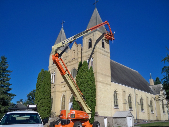 Roofing work being done on a steep church rooftop