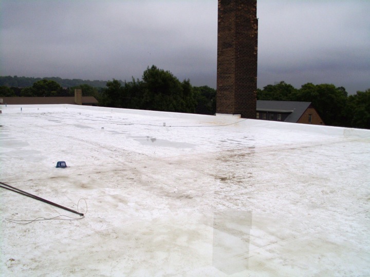 Commercial roof with a white membrane and pools of water