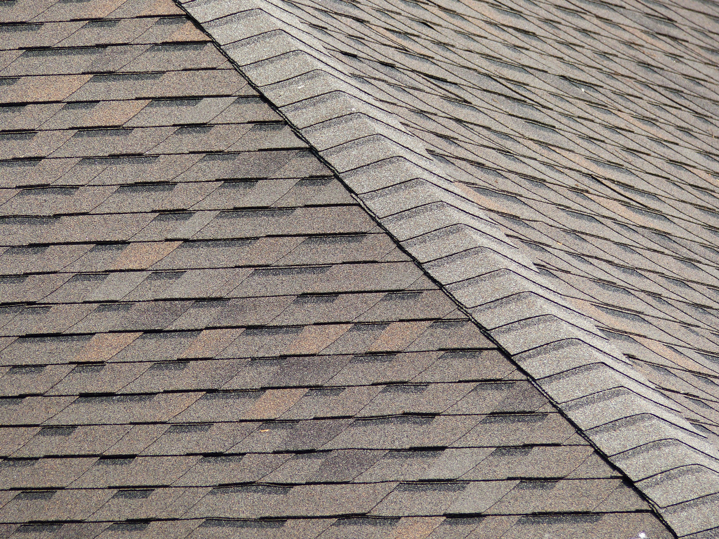 The seam of a rooftop with brown asphalt shingles
