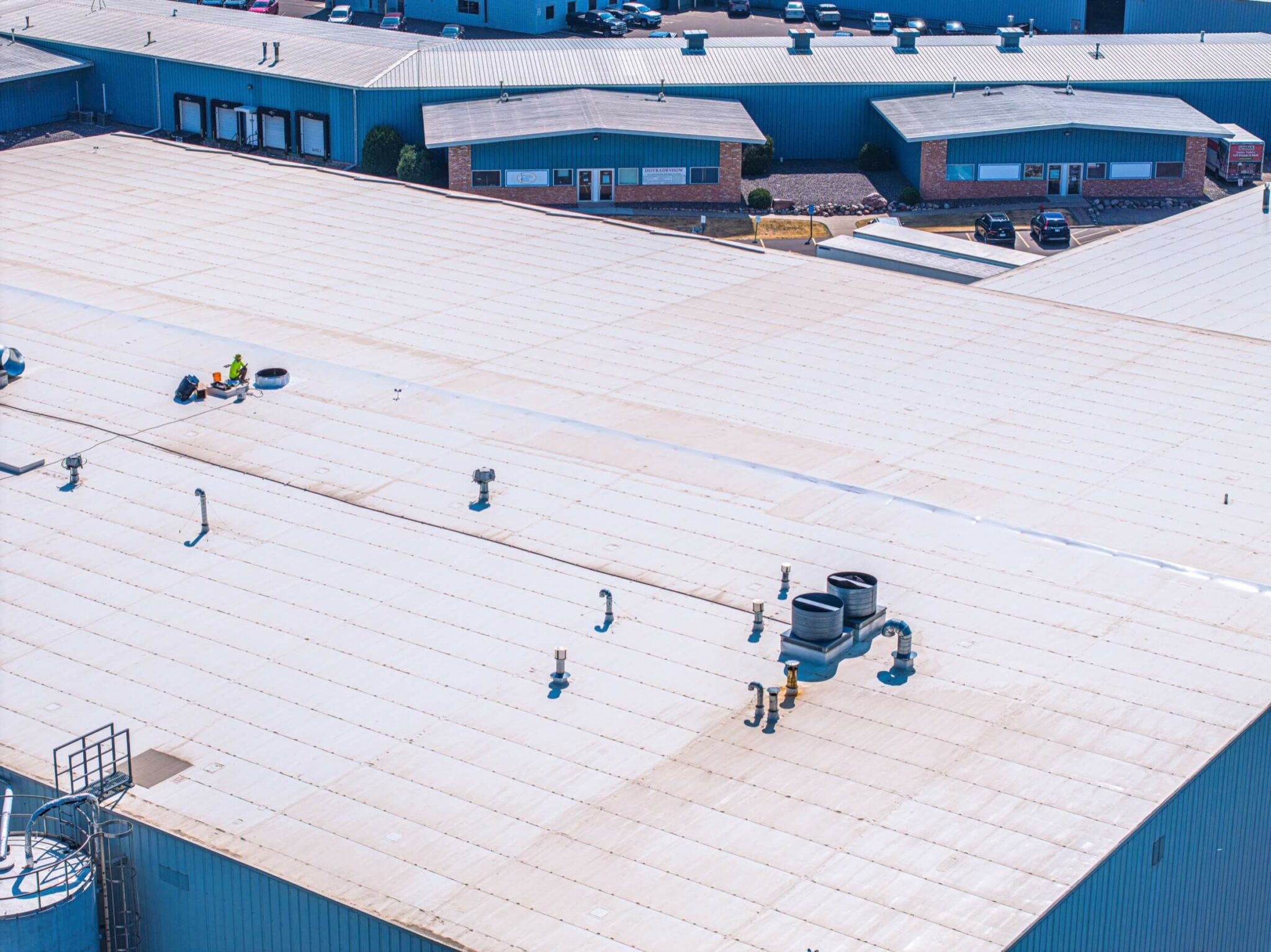 Roofer working in the middle of a large white rooftop