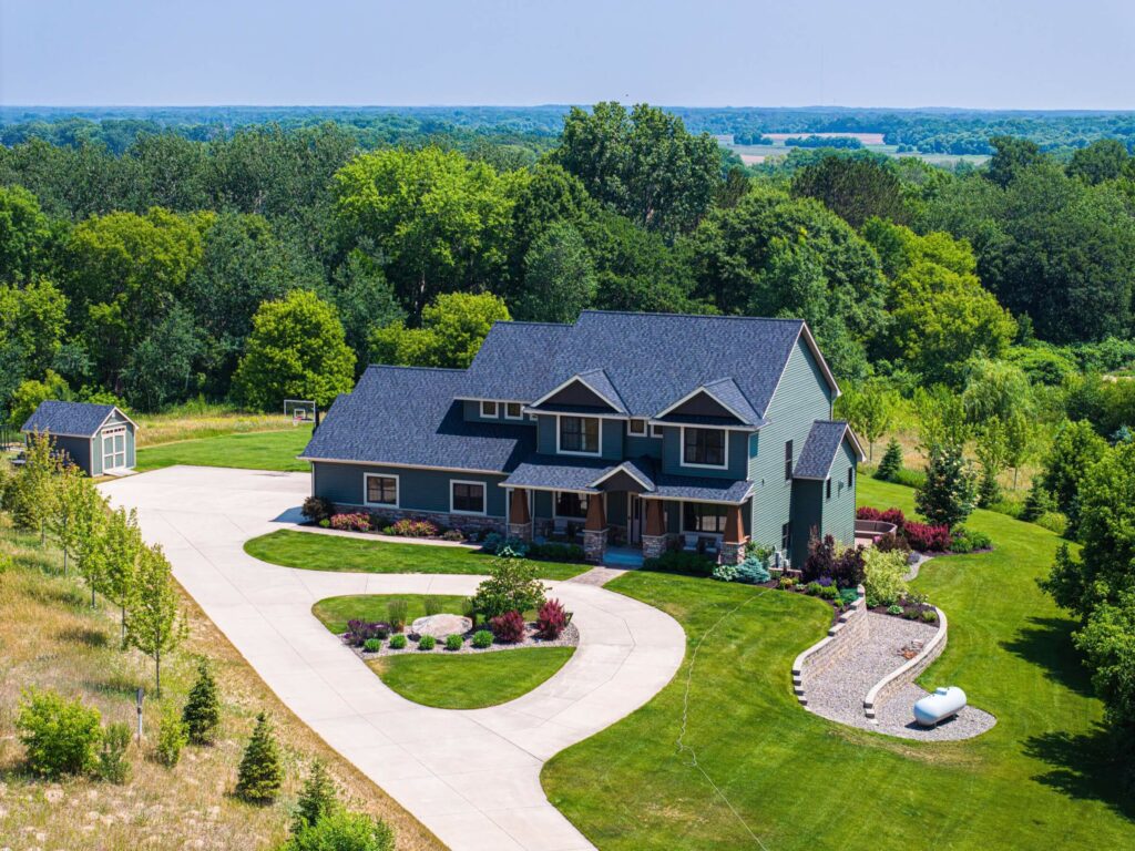 Green house with a large driveway and many yard features