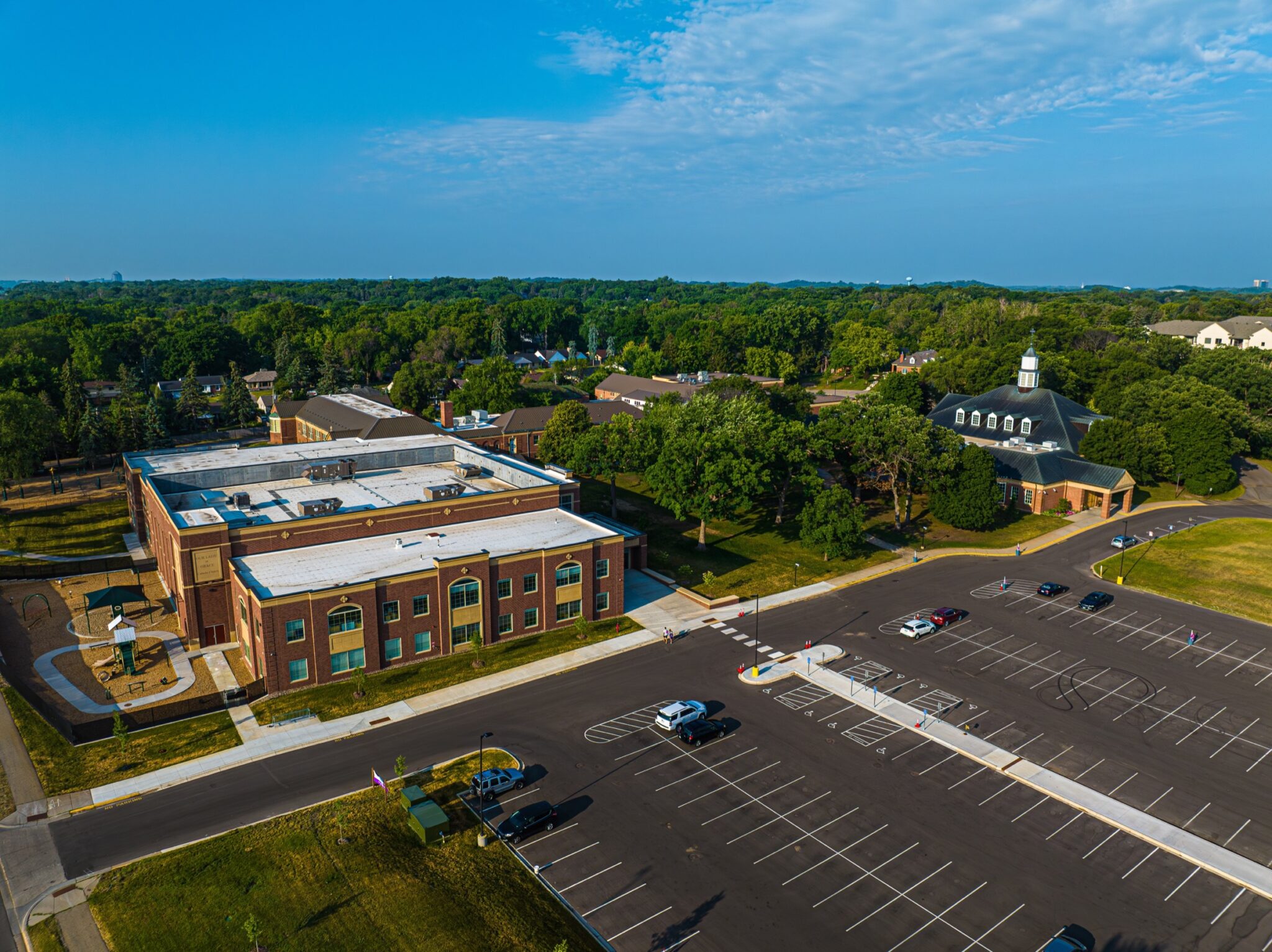 Aerial view of a school and church with a large shared parking lot